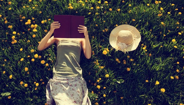 Girl lying in grass, reading a book.